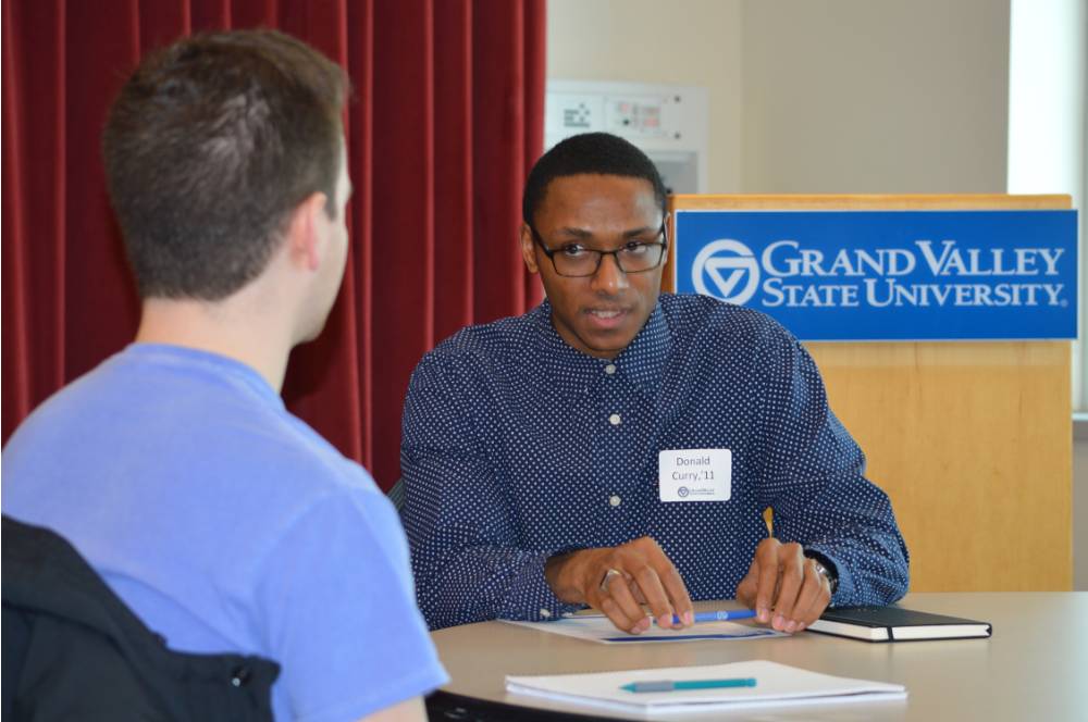 An alumnus explaining something to a student at the 30 Minute Mentors Event